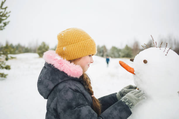 istock child sculpts makes snowman outdoors. kids fun in winter 1288816923