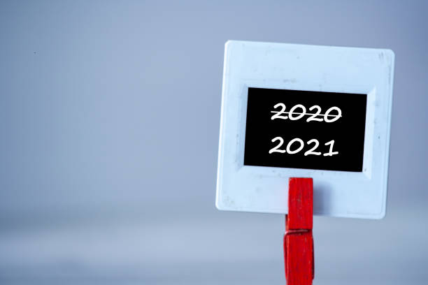 istock Plastic frame with clothes pin on table. White frame with black background and inscription word change 2020 to 2012 New Year 2021 1288818483