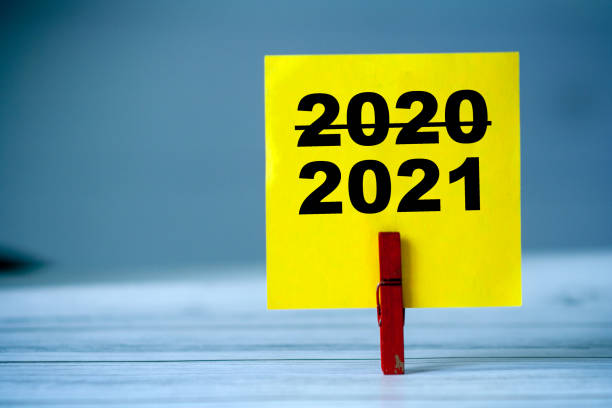 istock Reminder sticky note with clothes pin on table. Sticky note with crossed inscription 2020 and normal 2021. New Year 2021 1288818544