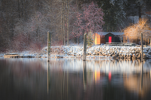 A lovely winter scene on Kootenay Lake with snow covered trees, rocks and cabins