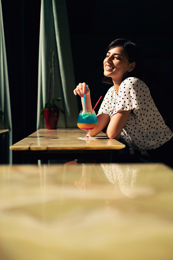 Young woman smiling and enjoy the moment while drinking her cocktail