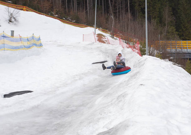 istock Mother and daughter go down the slide on an inflatable ring. 1288821434