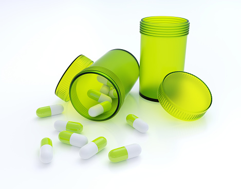 Green pill bottles with pills on white background