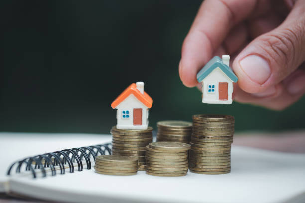a woman holding a house on a pile of coins is planning savings money. concept for property ladder, mortgage and real estate investment. for saving or investment for a house. - real estate imagens e fotografias de stock