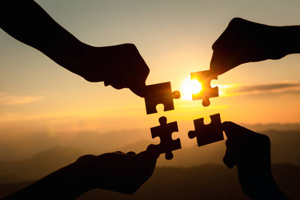 Silhouette  hands connecting  jigsaw puzzle piece against sunrise, Business solutions,  teamwork, partnership, success, goals and strategy concepts. Silhouette  hands connecting  jigsaw puzzle piece against sunrise, Business solutions,  teamwork, partnership, success, goals and strategy concepts. jigsaw puzzle photos stock pictures, royalty-free photos & images