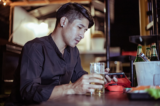 Stressed drunk man sitting alone with glass of beer in bar
