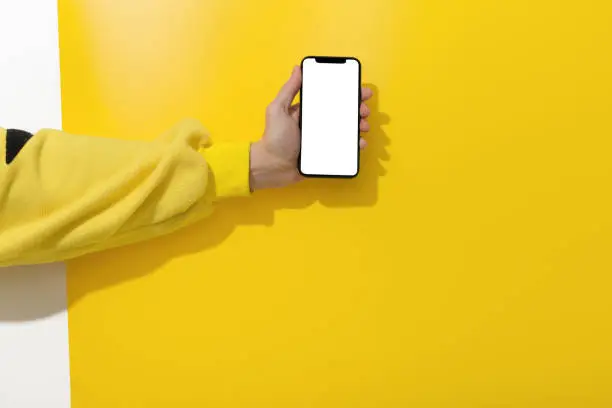 Hands holding smart phone on yellow background. Mockup concepts