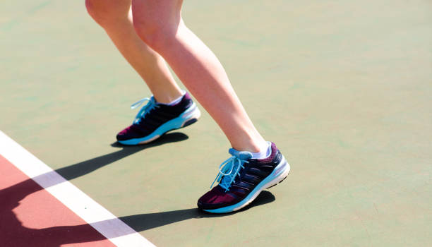 Legs of young girl in a closed tennis court with racket, sport shoes Legs of young girl in a closed tennis court with racket cropped pants photos stock pictures, royalty-free photos & images