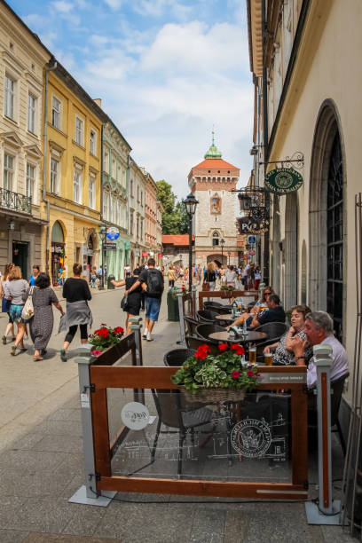 turistas sentados en una cafetería en la calle florianska en la puerta de san florián, en el casco antiguo de cracovia, polonia. - florianska street fotografías e imágenes de stock