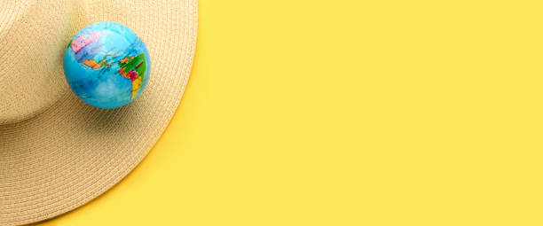 istock Tourist theme: hat, globe on a yellow background, empty space for text on the right. Travel accessories. The globe shows South America, North America, USA. Banner. 1288832613