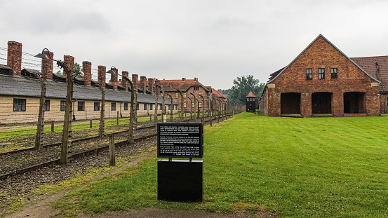 Auschwitz, Poland - July 30th 2018: Barbed wire fencing and an information sign at the SS execution site at Auschwitz Birkenau Nazi concentration camp, Poland