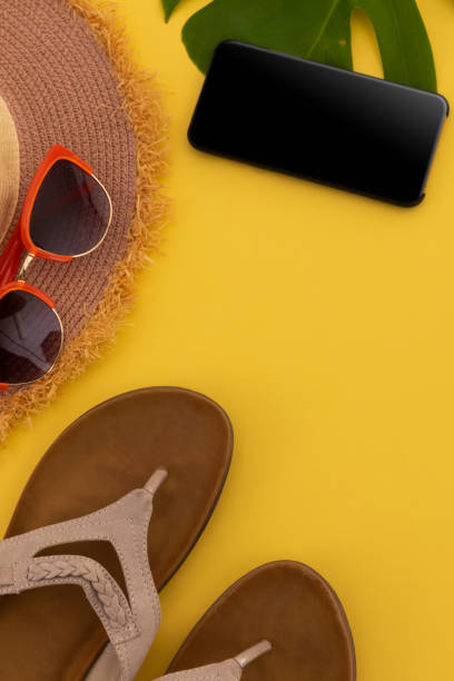 istock Sunglasses, flip flops, sunhat and smartphone on yellow background 1288833221