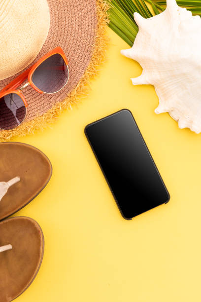 istock Sunglasses, flip flops, sunhat, shell and smartphone on yellow background 1288833226