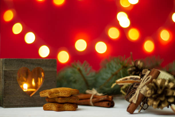 istock Wooden candlestick, gingerbread with Christmas tree branches and bokeh on a red background. 1288833416