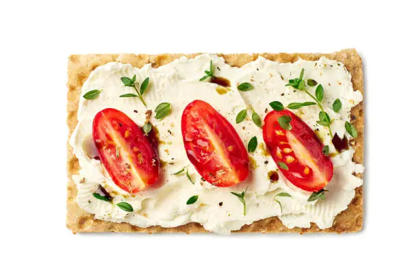 Bread crisps with cream cheese, tomato slices and herbs isolated on white. Clipping path included