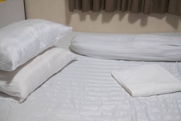 istock Close-up white bedding sheets and pillow with white towel. Fresh bed concept 1288834887