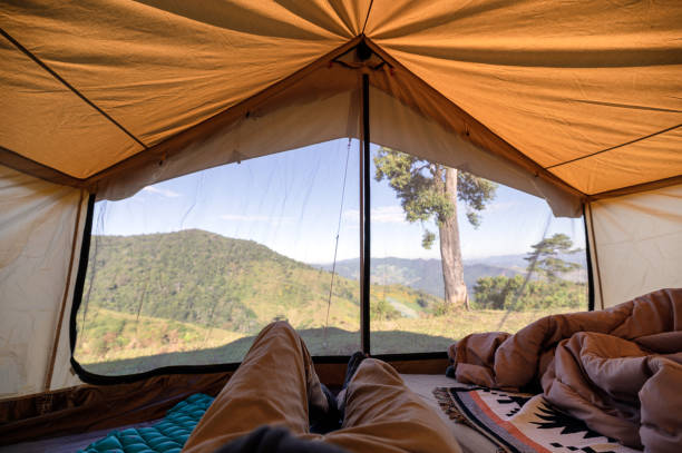 istock Man relaxing in a tent on hill with blue sky 1288835314
