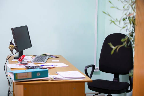 istock Work desk with laptop and paper and chair. Empty office during quarantine. 1288836773