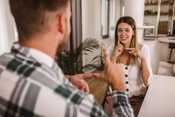 Young couple talking using sign language at home.
