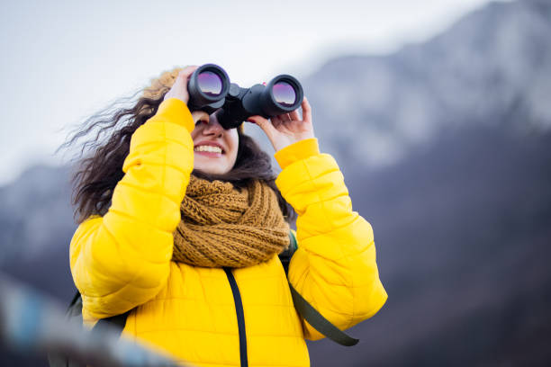 Young adventurous women looking trough binoculars stock photo