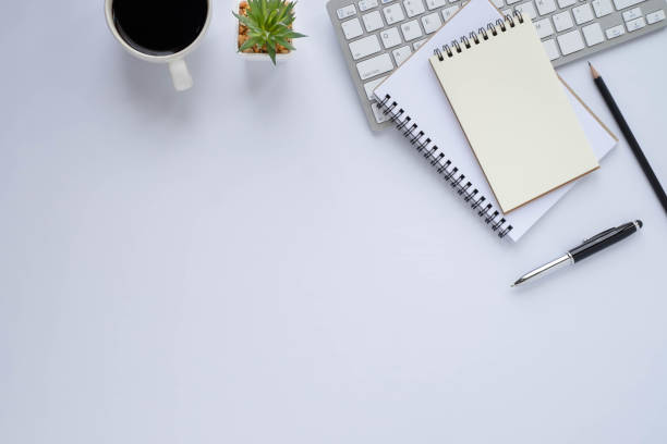 istock Top view above of White office desk table with keyboard, notebook and coffee cup with equipment other office supplies. Business and finance concept. Workplace, Flat lay with blank copy space. 1288839616