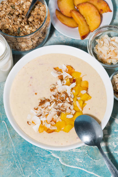 istock healthy smoothie bowl with mango, coconut and nuts for breakfast, closeup vertical 1288840119