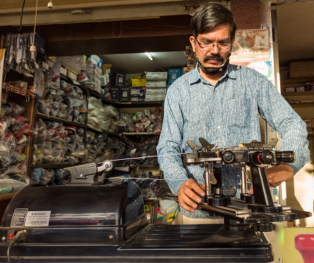 Aurangabad, India-11/13/2020; Weaving, Stringing badminton racket on racquet weaving machine. Repairing, Stringing Badminton manually by hands.