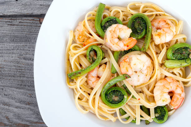 garlic linguini with shrimp and fiddlehead fern garlic linguini with shrimp and fiddlehead fern fiddle head stock pictures, royalty-free photos & images