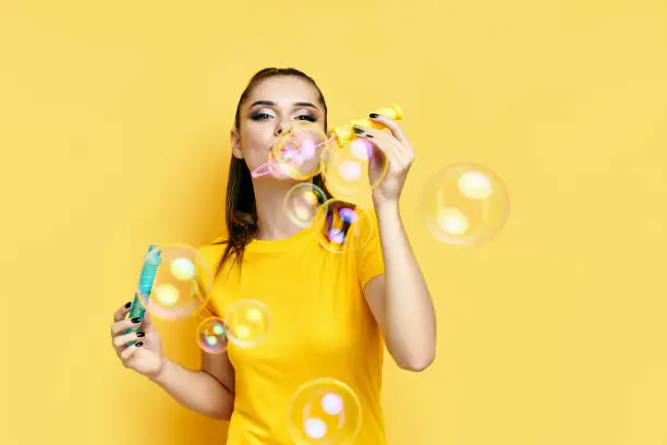 Photo of Happy beautiful woman blowing soap bubbles