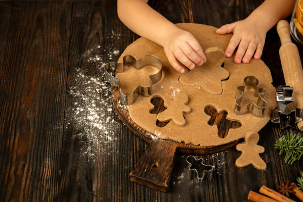 istock Little child hands making gingerbread men and festive decorations. 1288842636