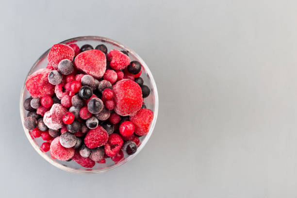 istock Frozen berries in glass bowl, raspberry, strawberry, cranberry and black currant, horizontal, copy space, top view 1288843786