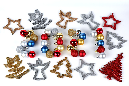 The 2021 lettering from gold, silver, blue and red christmas balls and different christmas decorations like angels, stars, trees, ribbons with bow on white background