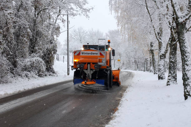 Snow plow is sprincling salt or de-icing chemicals on pavement in city. stock photo