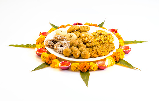Diwali snacks kept on Rangoli design made with flower petals of rose and marigold  for Diwali celebration in India