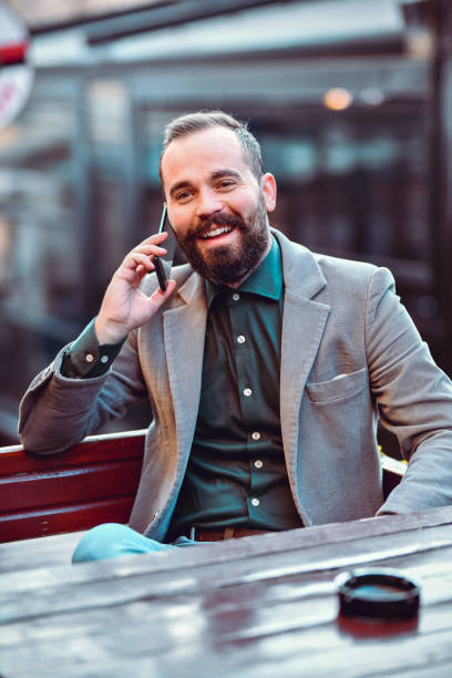 Bearded Male In Elegant Clothing Using Phone While Relaxing Outside