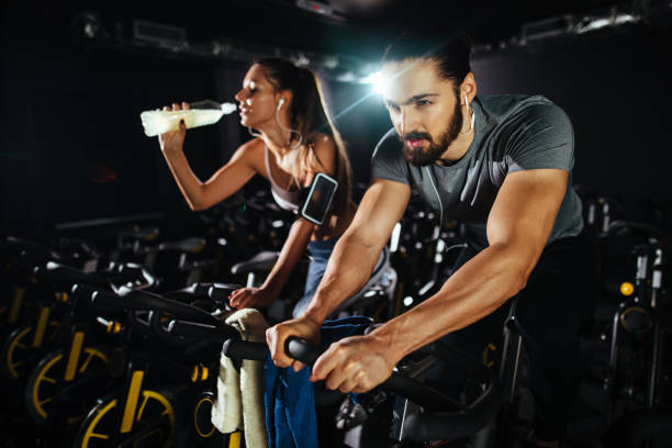 istock Two young people exercising on exercise bike at gym 1288844576