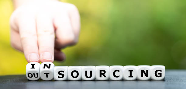 istock Hand turns dice and changes the word outsourcing to insourcing. 1288845640