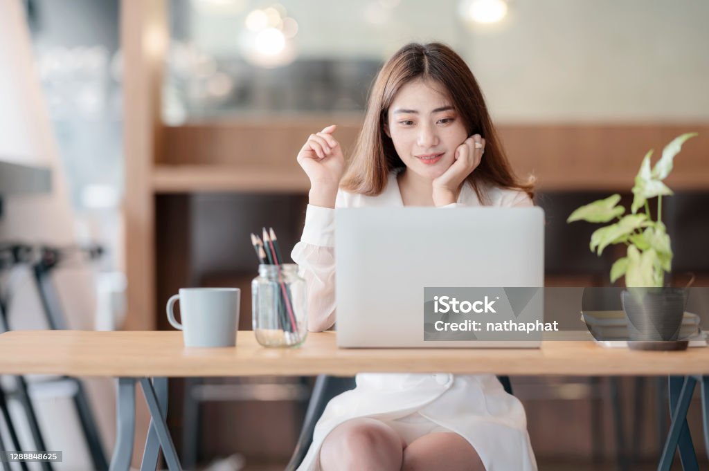Portrait of young asian woman working with laptop computer while sitting at her office desk. 25-29 Years Stock Photo