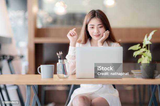 Portrait Of Young Asian Woman Working With Laptop Computer While Sitting At Her Office Desk Stock Photo - Download Image Now