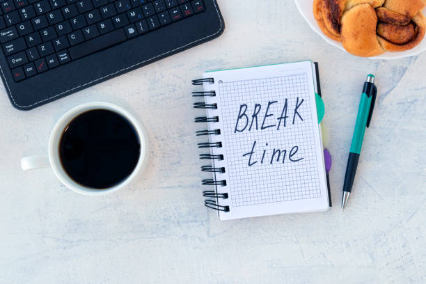 istock Break time. Concept time off. Words Break time in notebook on the working table with cup of coffee and bun. 1288850220