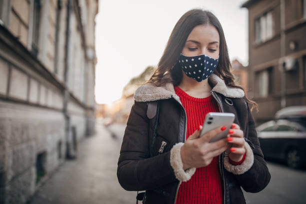 istock Woman with face mask using phone on the street 1288852673