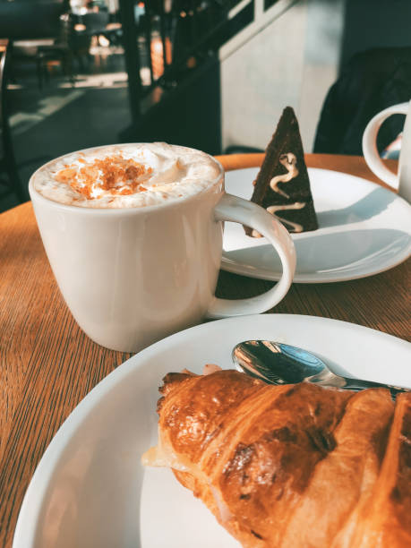 istock Coffee cup with cream, croissant and chocolate cake on a wooden table 1288852889