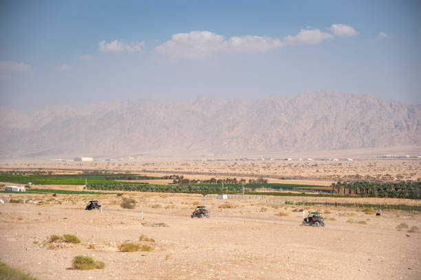 the border between israel and jordan against the backdrop of the aqaba mountains and the red sea. atvs in the field - travel jordan israel sand imagens e fotografias de stock
