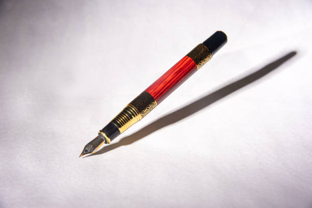 istock Antique fountain pen, fountain pen released in the air with drop shadow on light gray background, selective focus. 1288856428