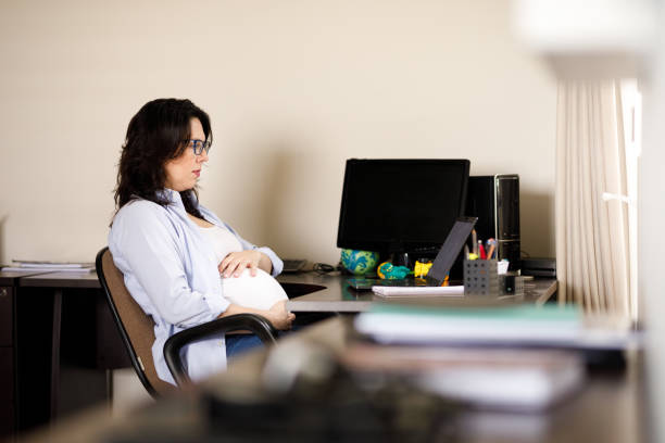 istock Pregnant woman working and looking at her laptop 1288856477