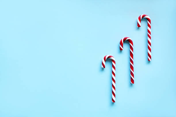 istock Three red-white caramel canes Christmas blue background. 1288856645