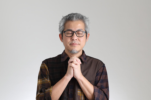 The senior Asian man standing on the white background