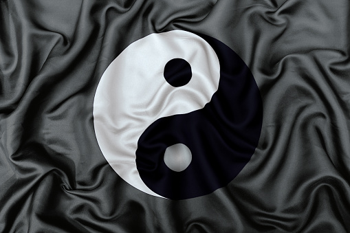 Yin and Yang symbol on a silk satin fabric texture background.