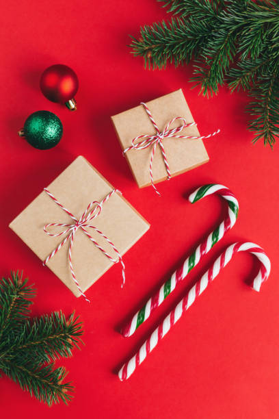 istock Gift boxes with christmass balls and candy canes on a red background. 1288870384