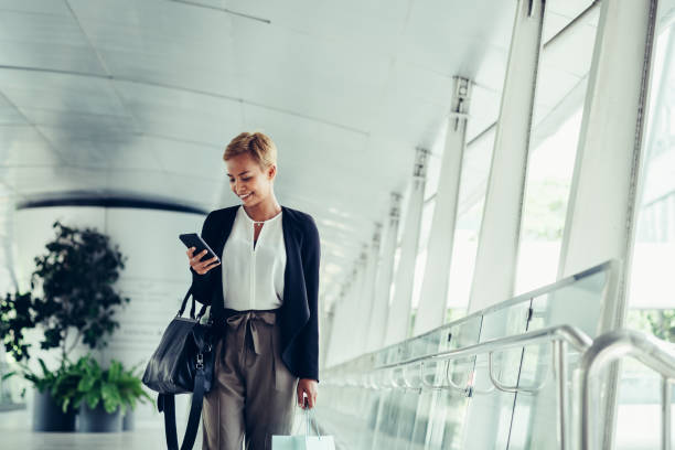 istock Happy business woman using mobile phone in modern corridor 1288870450